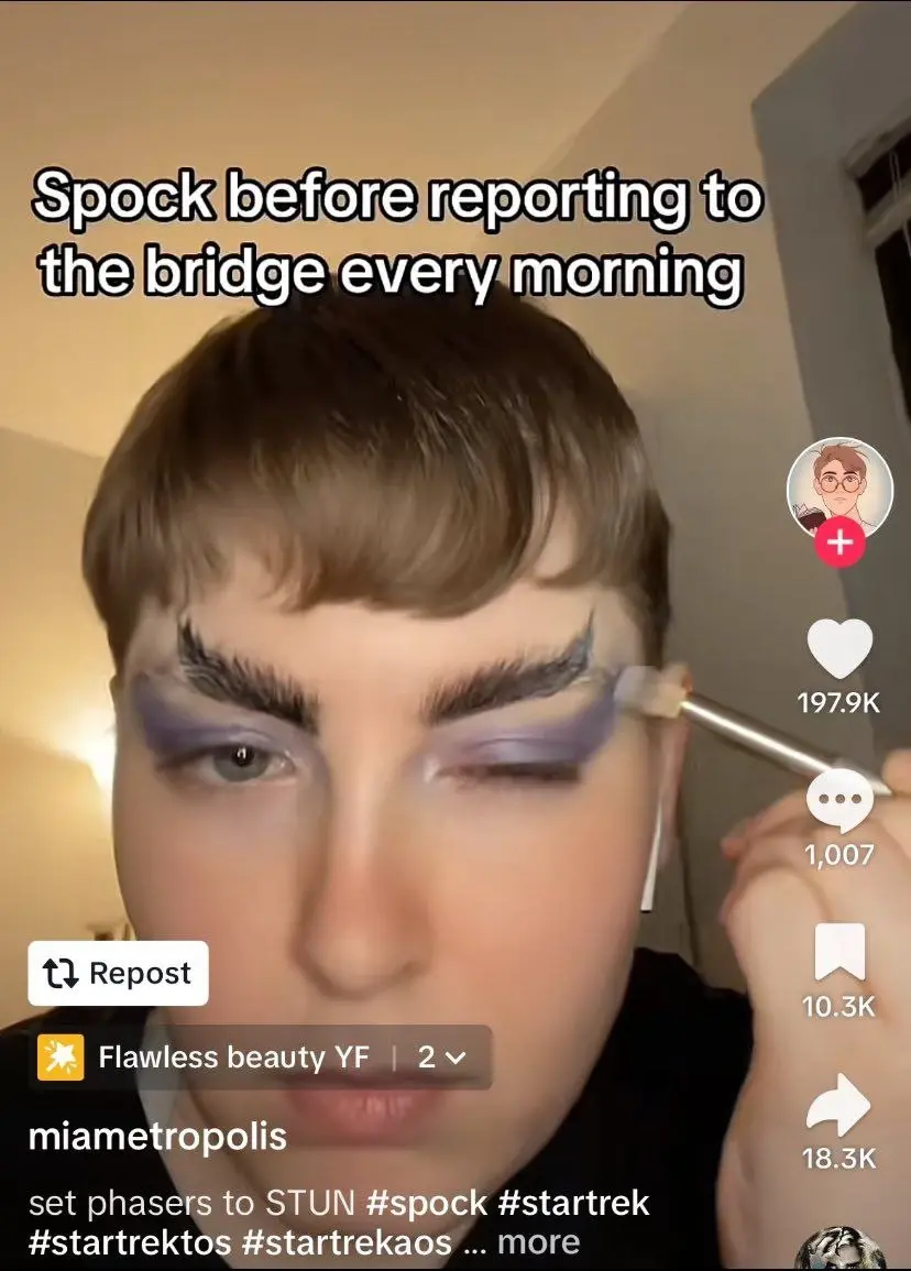 A screenshot of a TikTok that says “Spock before reporting to the bridge every morning”. The creator is holding an eyeshadow brush and applying deep purple eyeshadow above their eyes. They have also given themself Vulcan eyebrows. The overall effect is camp and obviously done by someone who knows a lot more about makeup than me 